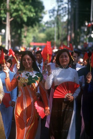 VIETNAM, Ho Chi Minh City, Young women holding flags and fans on the 25th Anniversary Parade for the liberation of Saigon.