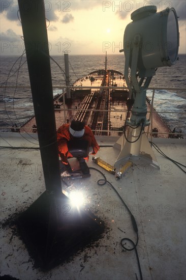INDUSTRY, Welding, Man using electric arc welder on board a ship in Indonesia.