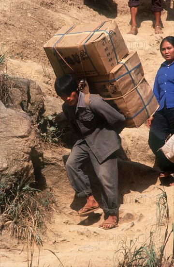 VIETNAM, Work, Smuggling on the Chinese border.  Heavily laden porter crossing to trade.