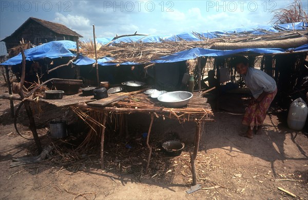 CAMBODIA, Kompong Thom, Phnom Prasat refugee camp.  Refugees in makeshift shelter with table and cooking pots in the foreground.