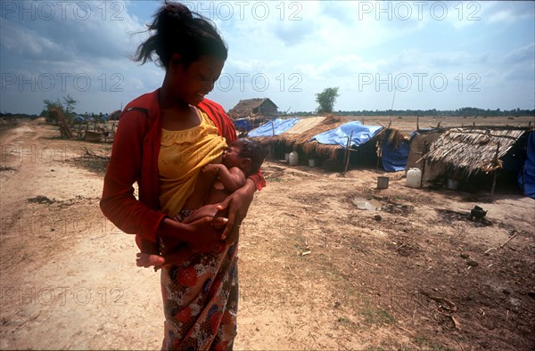 CAMBODIA, Kompong Thom, "Phnom Prasat Khmer Rouge refugee camp.  Young woman breast feeding her baby, line of makeshift shelters behind."