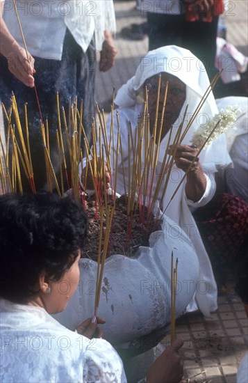 CAMBODIA, Phnom Penh, Wesak Festival.  Women lighting incense.