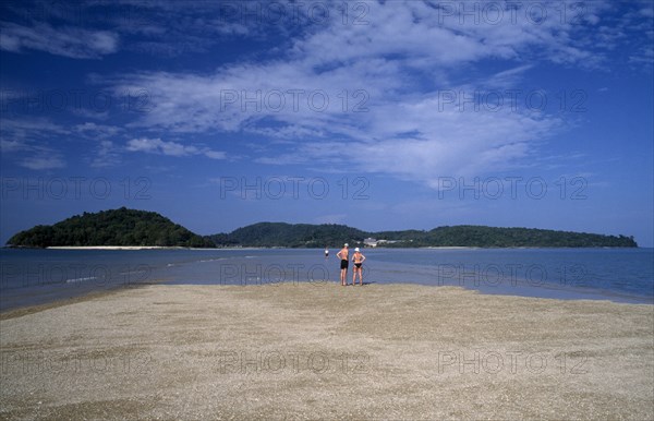 MALAYSIA, Langkawi, Kedah, Pantai Cenang beach with people walking on the sand bar at low tide to Pulau Rebak Kecil island