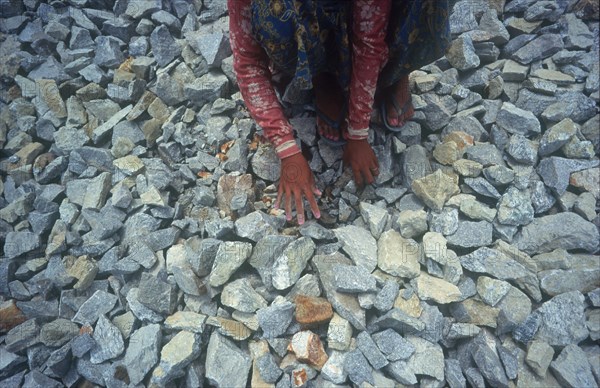 MYANMAR, Yangon, "Student forced labour working on the road to the War Cemetery.  Girl crouched to pick up stones, detail of hands. "