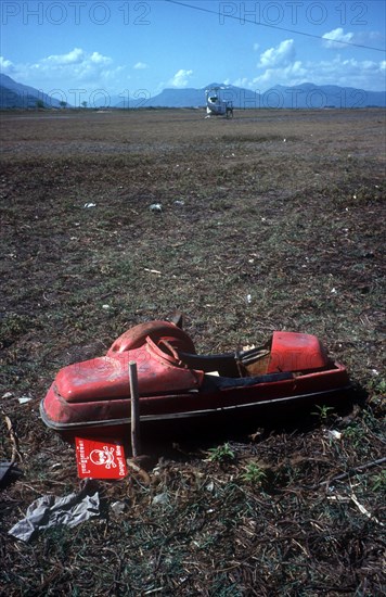 CAMBODIA, Work, Unexploded mine in a field on the Vietnamese border north west of Tinh Bien.  UN helicopter on the ground in the distance.