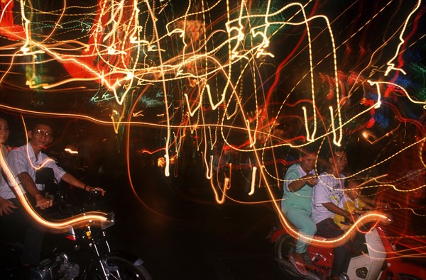 VIETNAM, Ho Chi Minh City, Motor cycle riders on the evening of Liberation Day and coloured light trails.