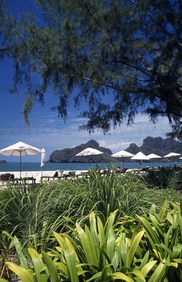 MALAYSIA, Kedah, Langkawi, Pantai Rhu beach from the gardens of the Radisson Resort hotel with umbrellas on the beach