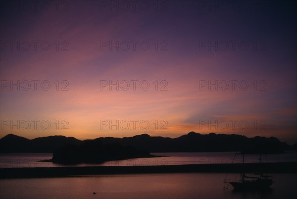 MALAYSIA, Kedah, Langkawi, Sunrise over Pulau Dayang Bunting island with schooner moored in the foreground
