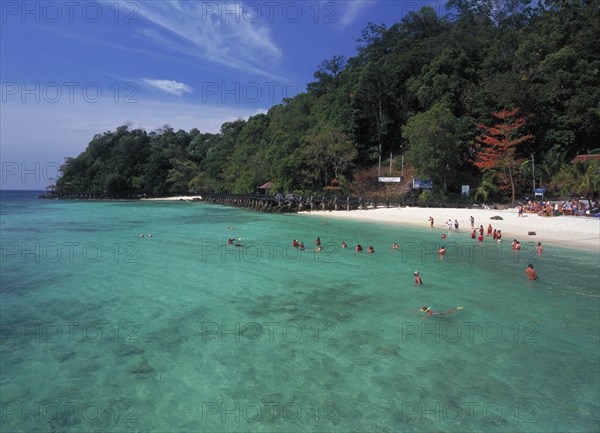 MALAYSIA, Kedah, Langkawi, Pulau Paya marine national park tree lined beach with tourists snorkling above the inshore coral
