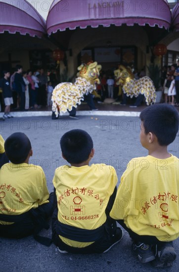 MALAYSIA, Kedah, Langkawi, Chinese New Year Dragon Dance with three children from the troupe in the foreground watching two dragons