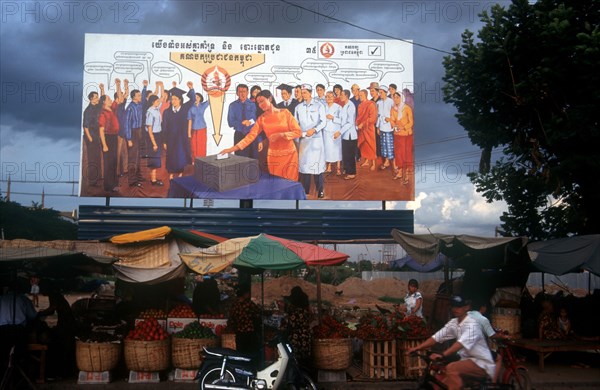 CAMBODIA, Phnom Pehn, Election poster with line of stalls selling fruit along the roadside in front.
