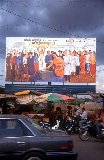 CAMBODIA, Phnom Pehn, Election poster with line of stalls selling fruit along the roadside in front.