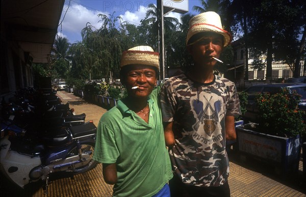 CAMBODIA, Phnom Pehn, Venteran amputees smoking cigarettes outside the Hotel Monorom.