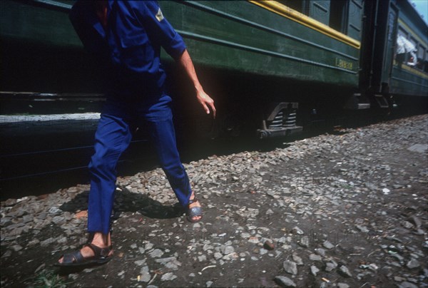 VIETNAM, Danang, Cropped shot of a figure walking alongside green train carriage.