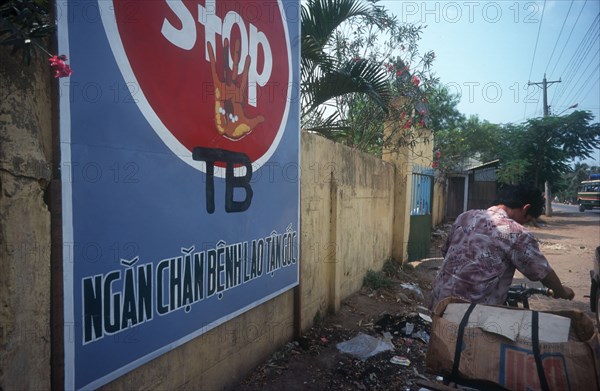 VIETNAM, Ben Tre , Cropped shot of a man walking with his bicycle past a poster warning about TB.