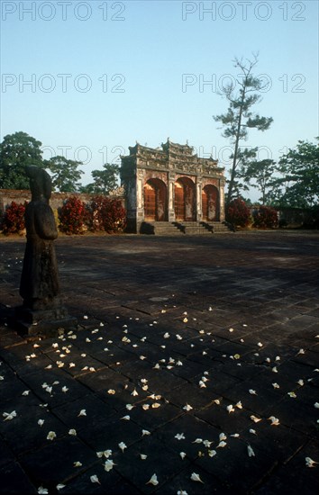 VIETNAM, Hue, Minh Mang Tomb.  View across courtyard scattered with flowers towards ruins with large stone statues on the left.