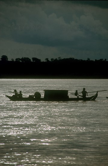 CAMBODIA, Stung Treng, "Narrow barge on the Mekong River, oarsmen silhouetted against sparkling water."
