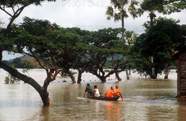 CAMBODIA, East, Two Budhist monks in a canoe being rowed through flood water on Route 1 from Neak Long to Svay Rieng.