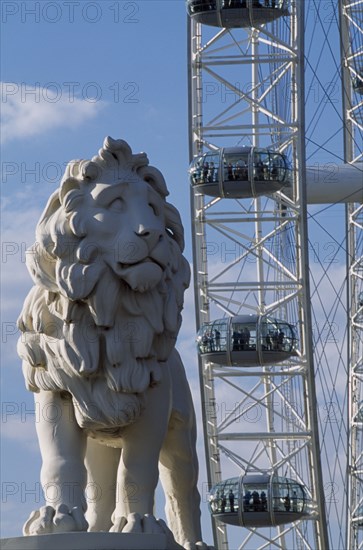 ENGLAND, London, "The London Eye, part view of the wheel rim with capsules and passengers behind statue of standing lion in the foreground  "