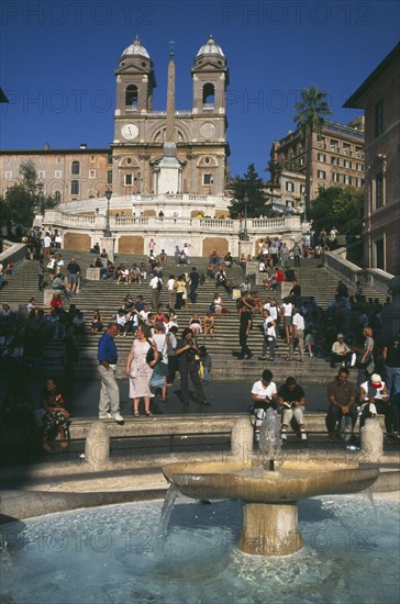 ITALY, Lazio, Rome, Piazza di Spagna. Fountain in the foreground with people on the Spanish Steps behind.