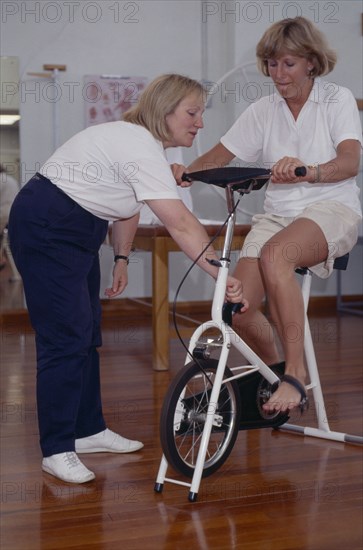 20010198 SPORT Injuries Physiotherapist Female sport physiotherapist with female patient on exercise bike