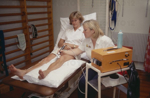 20010200 SPORT Injuries Physiotherapist  Female sport physiotherapist using ultra sound treatment on female patients leg