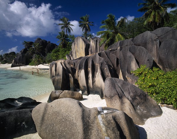 SEYCHELLES, La Digue, Source De L’Argent, "Large, smoothly eroded rocks with graduated colour tones and tidemarks.  Clear blue water, palm trees and stretch of white sand behind. "