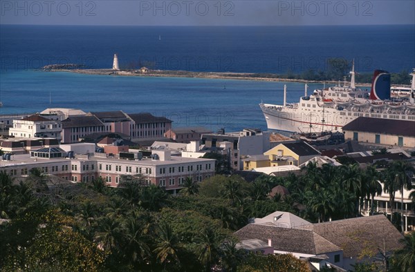 BAHAMAS, Nassau, View over houses to harbour with a cruise ship at dockside and a lighthouse in the distance