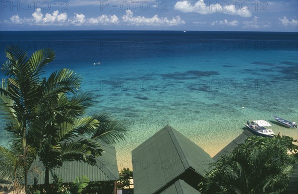 MALAYSIA, East Coast, Pulau Tioman Island, "Panuba Bay, north west coast. View over palm trees and beach hut roof tops towards sea and horizon. "