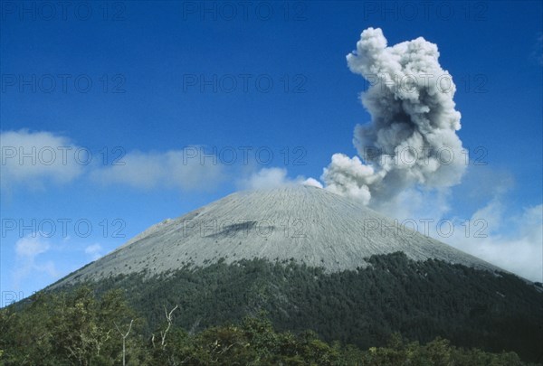 INDONESIA, Java, Mount Semeru, Smoke rising from the volcano as it erupts above the tree lined base with dust surrounding the summit