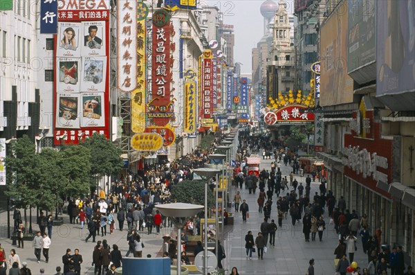 CHINA, Shanghai, Pedestrianised street crowded with shoppers and lined with advertising hoardings and neon signs.