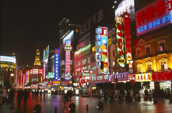 CHINA, Shanghai, Busy pedestrianised street with neon signs and advertising hoardings illuminated at night.