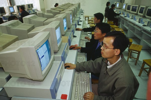 CHINA, Shaanxi Province, Xian, Internet Cafe with men seated at rows of computers.