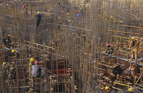 CHINA, Shaanxi Province, Xian, Construction workers on scaffolding amongst steel fixing on a building site.
