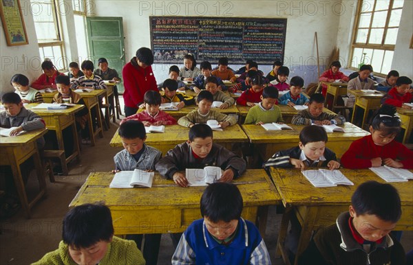 CHINA, Shaanxi Province, Xian, Classroom with school children reading at their desks with a teacher.