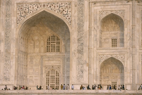 INDIA, Uttar Pradesh, Agra, "The Taj Mahal, detail of patterned marble walls with visitors below."