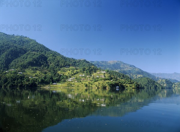 NEPAL, Annapurna Region, Pokhara, View over Lake Phewa with reflected terrace hillside and trees.