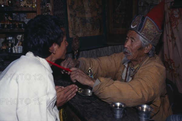 NEPAL, Annapurna Region, Manang, Lama blessing good luck thread for safe journey.  Also known as the 1000 rupee lama due to the cost of the blessing.