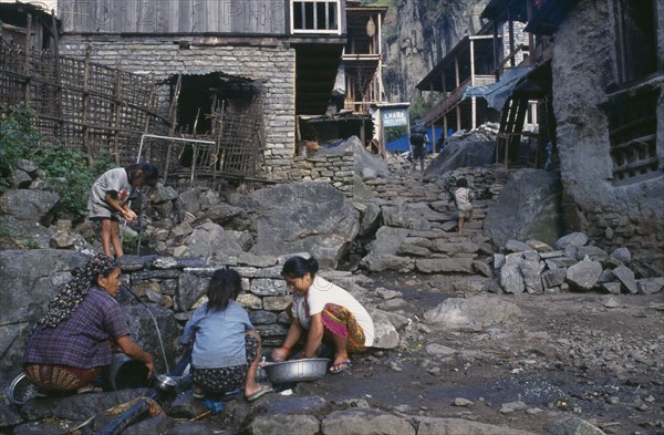 NEPAL, Annapurna Region, Dharapani, Women and children washing at piped water source in village.