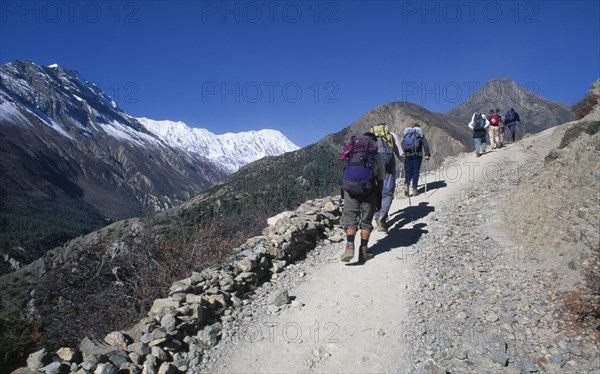 NEPAL,  , Annapurna, "Group of trekkers carrying rucksacks walking up steep mountain path, seen from behind."