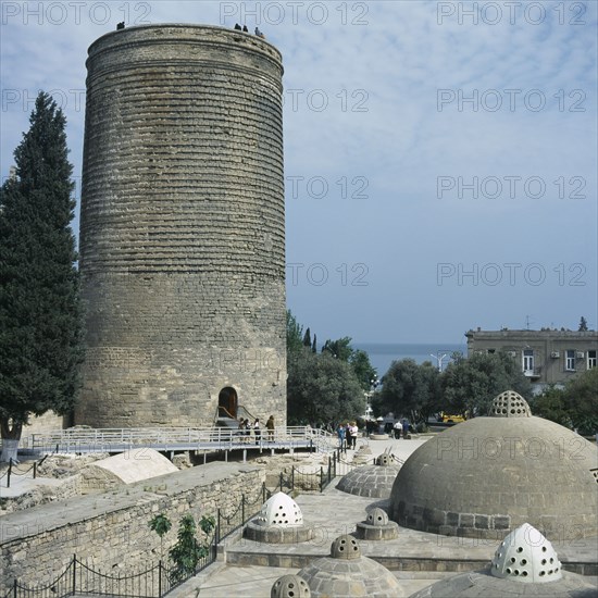 AZERBAIJAN, Baku, Icheri Shahar, Maidens Tower.  Circular stone tower with visitors standing on the top and at the entrance below.