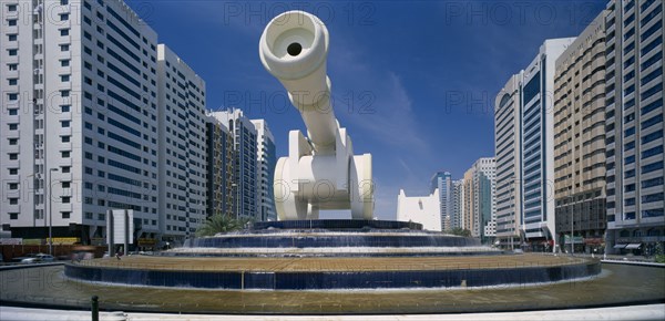 UAE, Abu Dhabi, Al-Ittihad Square with huge sculpture of a cannon set on a circular tiered waterfall with modern high rise buildings on each side.