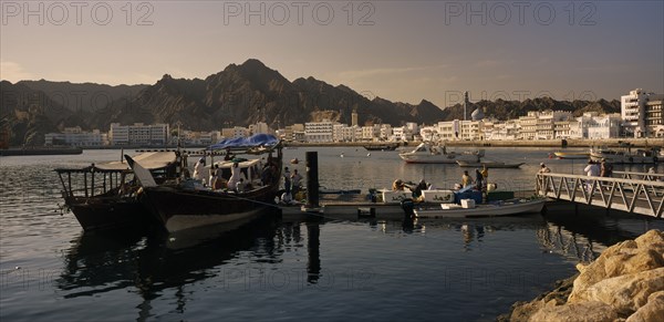 OMAN, Muscat, Mutrah Fish Market.  Fishing boats landing catch with waterside buildings behind.