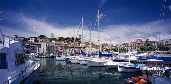 FRANCE, Provence-Cote d’Azur, Cannes, "The Old Port, view over moored boats towards waterside buildings.  Alpes Maritimes"