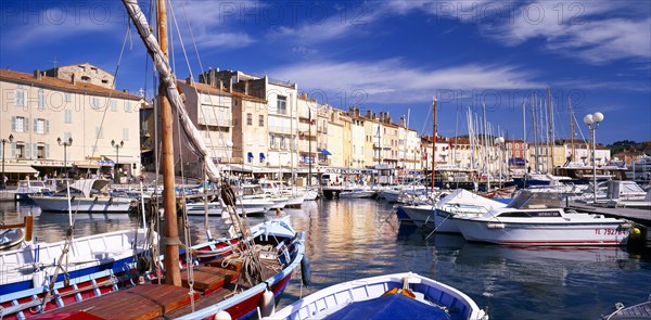 FRANCE, Provence-Cote d’Azur, St Tropez, View over harbour and moored boats towards waterside buildings.  Var.