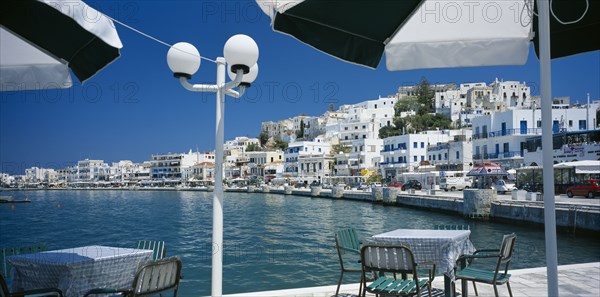 GREECE, Cyclades Islands, Naxos, "Hora.  View from waterside eating area under black and white sun umbrellas, towards white painted town buildings."