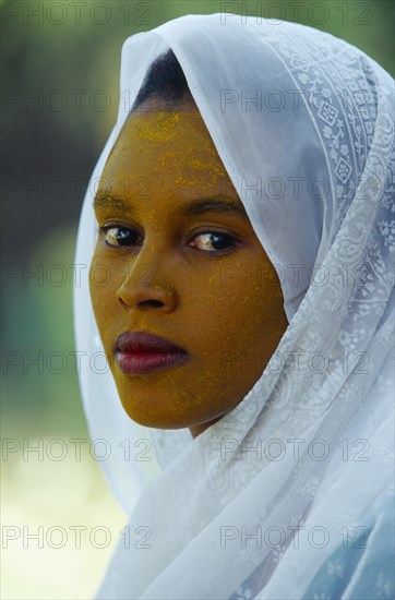 ETHIOPIA, Harerge Province, General, Portrait of young woman in white head covering with face stained with yellow powder.
