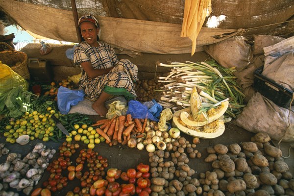 ETHIOPIA, Harerge Province, Harer, Market outside the city walls.  Female vendor sitting behind display of vegetables laid out on the ground in front of her.