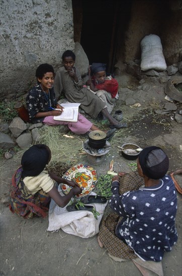 ETHIOPIA, Wolo Province, Lalibela, Group of woman and children sitting around cooking pot on stove outside building doorway.