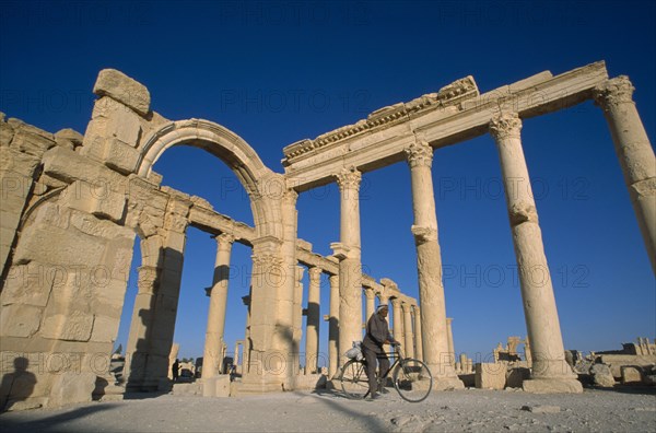 SYRIA, Central, Tadmur, Colonnade and archway with man on a bicycle framed between columns.